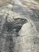 Foto: Schlaglöcher ,Hecke von Grundstück ragt in die Straße  
